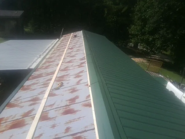 Old rusted panels beside newly installed green metal roofing — Wind Damage Roof Repair by Roofing Brothers in Elgin