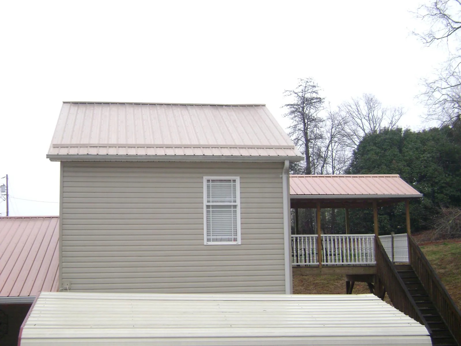 Tan metal roofs on a two story addition and attached porch, from a Roof Replacement job in Elgin